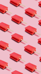 Pattern of pink kitchen sponges with wooden sticks on a pastel pink background. Ice creams made of sponges, dish washing. Household cleaning, taking care of hygiene. Creative summer concept.