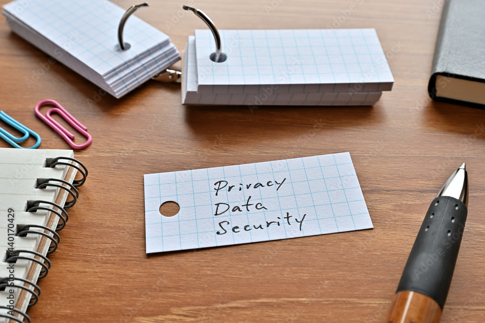 Poster there is a word book with the word privacy data security written on it with a pen and notebook.