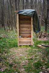 Outdoor wooden toilet surrounded by trees in a forest
