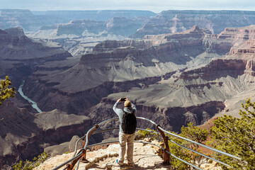 A man standing on the overlook taking picture of the formations of Grand Canyon, Arizona, USA