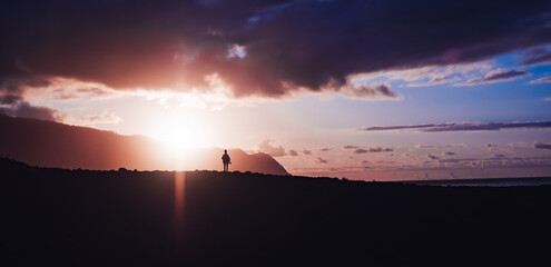 Panoramic silhouette of a girl standing on the cliff under the colorful cloudy sunset sky