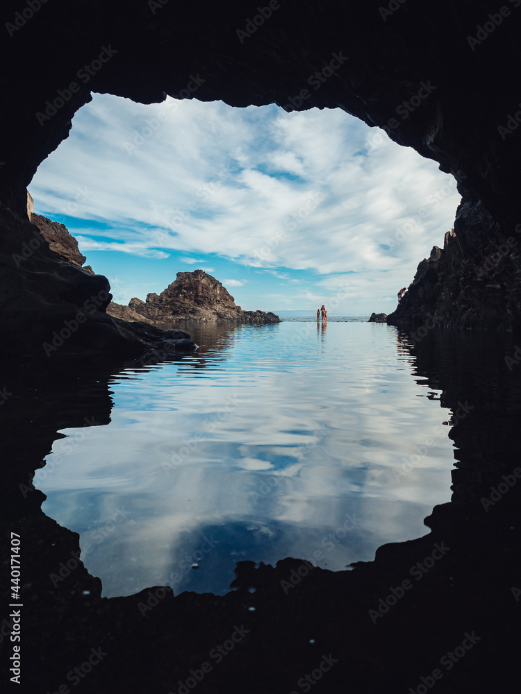 Canvas Prints Vertical shot of a rocky sea under a cloudy sky from a cave