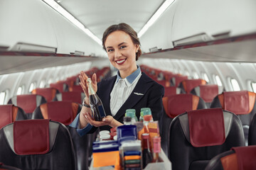 Stewardess show bottle with alcohol in airplane