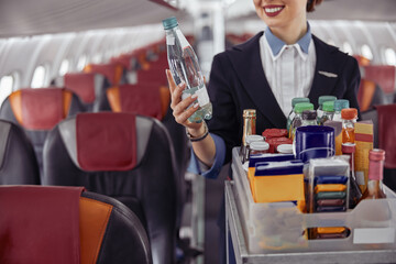 Stewardess holding water bottle in airplane cabin