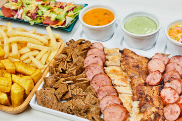 variety of grilled meats and chorizos with salad and french fries