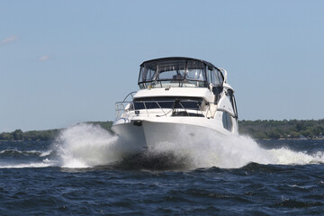 Large Cruiser going at a very fast clip due to heavy waves on bright summer day in Bay of Quinte