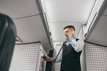 Flight attendant talk on board phone in airplane