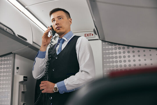 Flight Attendant Talk On Board Phone In Airplane