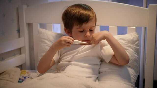 Upset little oy feeling sick coughing and measuring body temperature. Concept of children illness, disease and healthcare