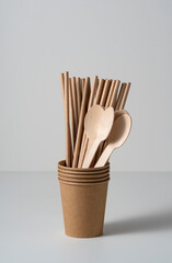 Disposable paper cups, straws, and spoons on a white background. Zero-waste concept.