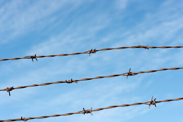 old, rusty barbed wire against blue sky