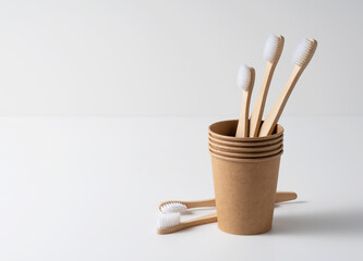Disposable paper cups and bamboo toothbrushes on a white background. The zero-waste concept.