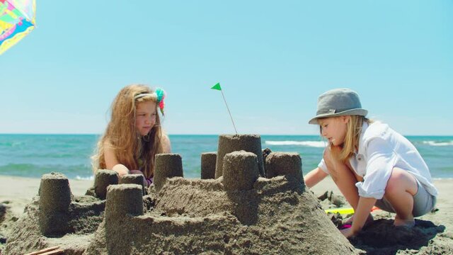 Close-up of nice sandcastle on beach, boy and girl playing with sand and chatting. Sunny summer day at seaside.