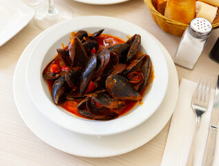 Delicious boiled mussels with tomato sauce and parsley in copper cooking dish