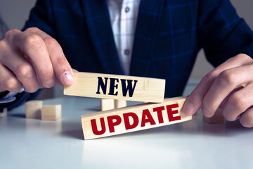 Obraz premium Businessman pressing his finger on the wooden cubes with the word new update. Download a new software or technology update concept.