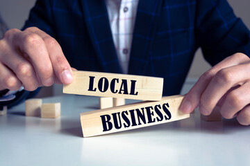 Obraz premium businessman holds wooden blocks with the inscription local business. small business development concept