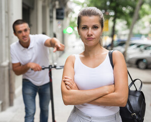 Young man on electric scooter talk to his offended girl on street