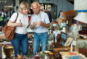 Fototapeta na wymiar Elderly couple in flea market chooses antique items