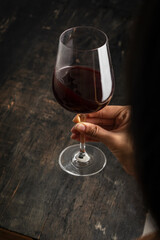 HAND HOLDING WINE GOWL ON RUSTIC BACKGROUND