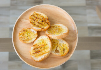 Selective focus and lay flat view of grilled garlic bread sliced with butter and spice looks delicious with yellow color for snack or appetizer for morning food or lunch served in restaurant.
