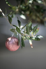 Vertical shot of a Christmas tree ball hanging on an olive tree