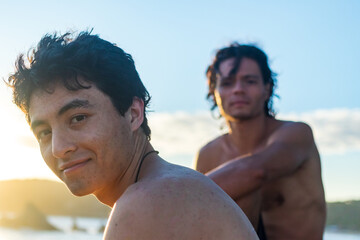 Closeup of two shirtless Mexican guys looking into the camera at the beach