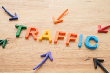 Marketing business, commerce and digital marketing strategy concept. Color highlight arrows pointing around TRAFFIC letters alphabets on wooden background.