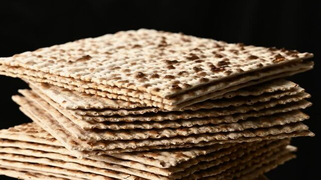stack of baked square matzo rotate on black background, kosher food