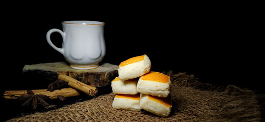 Closeup composition of Tea setup with baked biscuits or cookies and tea cup decorated with Cinnamon roll and star anise in a isolated rustic background. Butter biscuits.Pastry. Dark food photography.