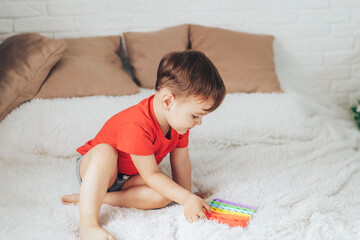 Little boy playing with child's toy on the bed