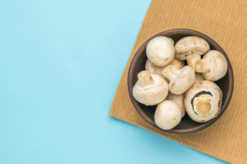 Clay bowl with large mushrooms on a blue background.