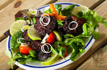 Traditional Spanish blood sausage with rice served with mix of greens, vegetables and lime
