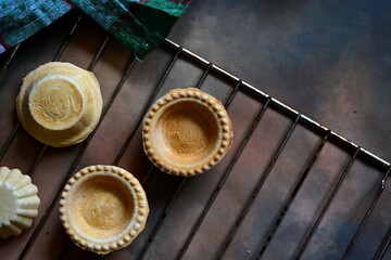 Homemade empty baked sponge tartlets close up on the grill cooking wrapped in kitchen towel. Top view with copy space