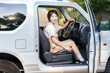車の運転席に座る若い女性