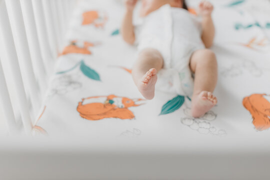 Beautiful Asian newborn baby feet in a baby cot. Happy parenthood and maternity conceptual image. Closed up soft focus.