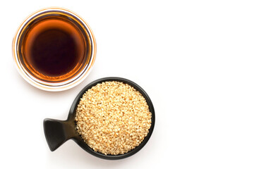 white Sesame oil with sesame seeds in black and white ceramics bowl isolated on white background.