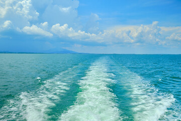 Fototapeta premium White bubbles and splashes of waves on the stern of the ferry that holiday traveled to the Sea of ​​Thailand in a blue sky. The ship was moving fast in the view of the ocean and nobody on the deck.