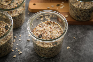Brotteig von Vollkorn Brot mit Kürbiskernen, Haferflocken, Sonnenblumenkernen, Chia und Leinsaat roh im Glas für Einkochen und Vorrat auf Holzbrett und Marmor Hintergrund dunkel