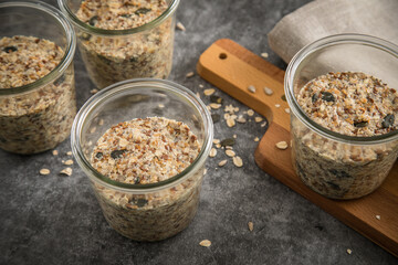 Brotteig von Vollkorn Brot mit Kürbiskernen, Haferflocken, Sonnenblumenkernen, Chia und Leinsaat roh im Glas für Einkochen und Vorrat auf Leinentuch, Holzbrett und Marmor Hintergrund dunkel