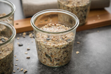 Brotteig von Vollkorn Brot mit Kürbiskernen, Haferflocken, Sonnenblumenkernen, Chia und Leinsaat roh im Glas für Einkochen und Vorrat auf Leinentuch, Holzbrett und Marmor Hintergrund dunkel