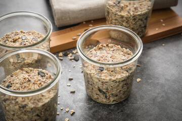 Brotteig von Vollkorn Brot mit Kürbiskernen, Haferflocken, Sonnenblumenkernen, Chia und Leinsaat roh im Glas für Einkochen und Vorrat auf Leinentuch, Holzbrett und Marmor Hintergrund dunkel