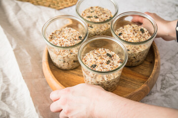 Brotteig von Vollkorn Brot mit Kürbiskernen, Haferflocken, Sonnenblumenkernen, Chia und Leinsaat roh im Glas für Einkochen und Vorrat auf Leinentuch, Holzbrett und Marmor Hintergrund hell
