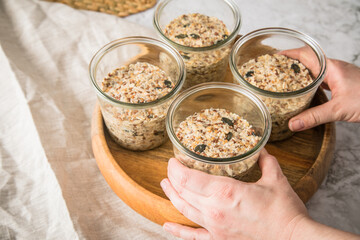 Brotteig von Vollkorn Brot mit Kürbiskernen, Haferflocken, Sonnenblumenkernen, Chia und Leinsaat roh im Glas für Einkochen und Vorrat auf Leinentuch, Holzbrett und Marmor Hintergrund hell