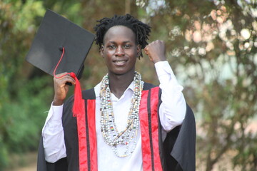 The African traditional man graduates on his graduation day and is looking straight into the camera with a wonderful smile with the African beads in his neck