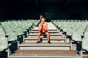 front view of a fit and healthy woman workingout at the stadium jumping up and down the steps at...