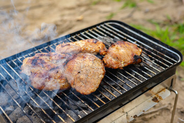 Steak on compact charcoal grill for travel in the cooking process.