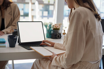 Cropped shot of businesswoman working,typing on white screen tablet computer.