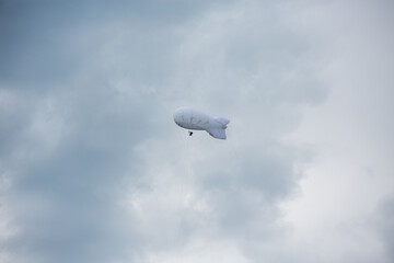 a balloon with a video surveillance camera high in a cloudy sky