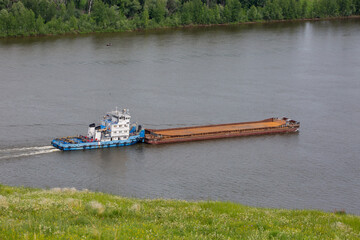 Nizhnekamsk, Tatarstan, Russia - 06.16.2021: A pusher vessel with an empty barge goes along the Kama river - obrazy, fototapety, plakaty