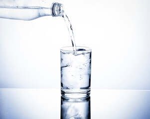 glass of water with ice and pouring water into a glass placed on a white background table